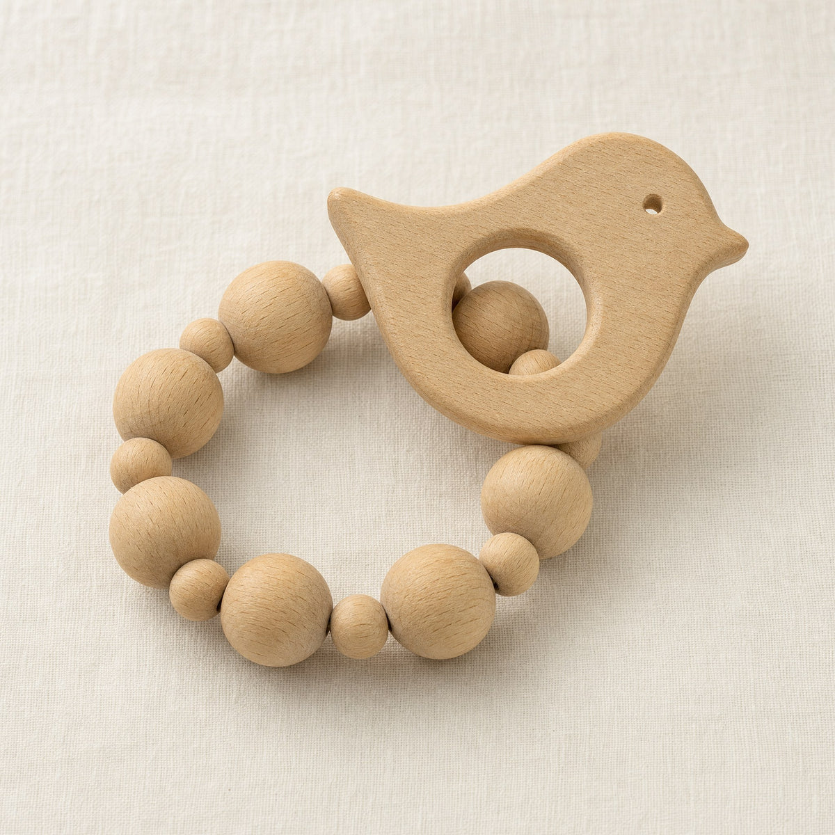 Anneau de dentition oiseau en bois naturel avec perles en bois, fond crème
