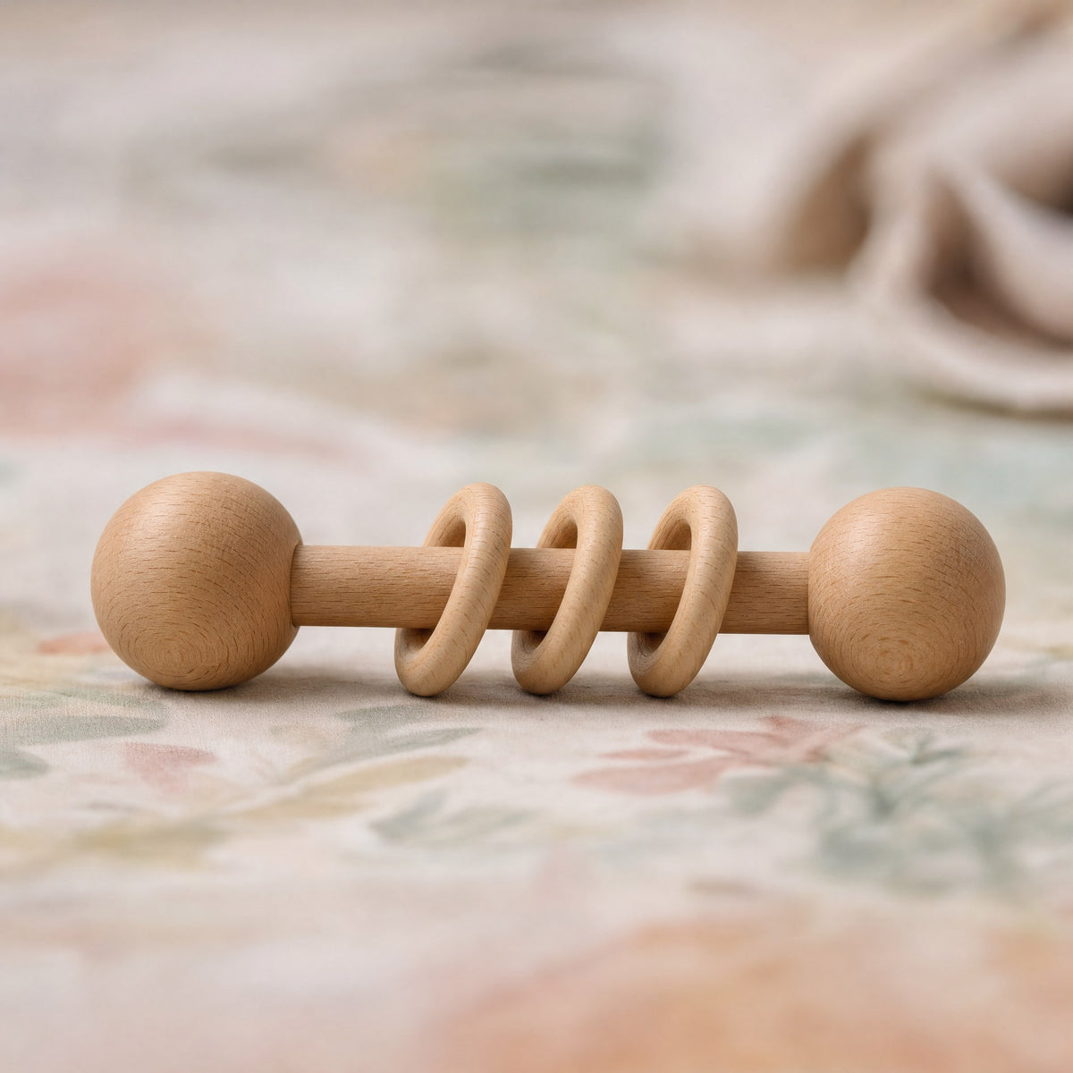 Hochet en bois posé sur un tapis de jeu bébé