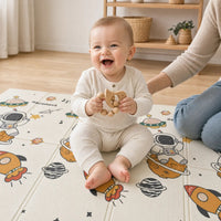 Bébé souriant tenant l'anneau de dentition oiseau en bois sur le tapis de jeu ECLOA Astronaute