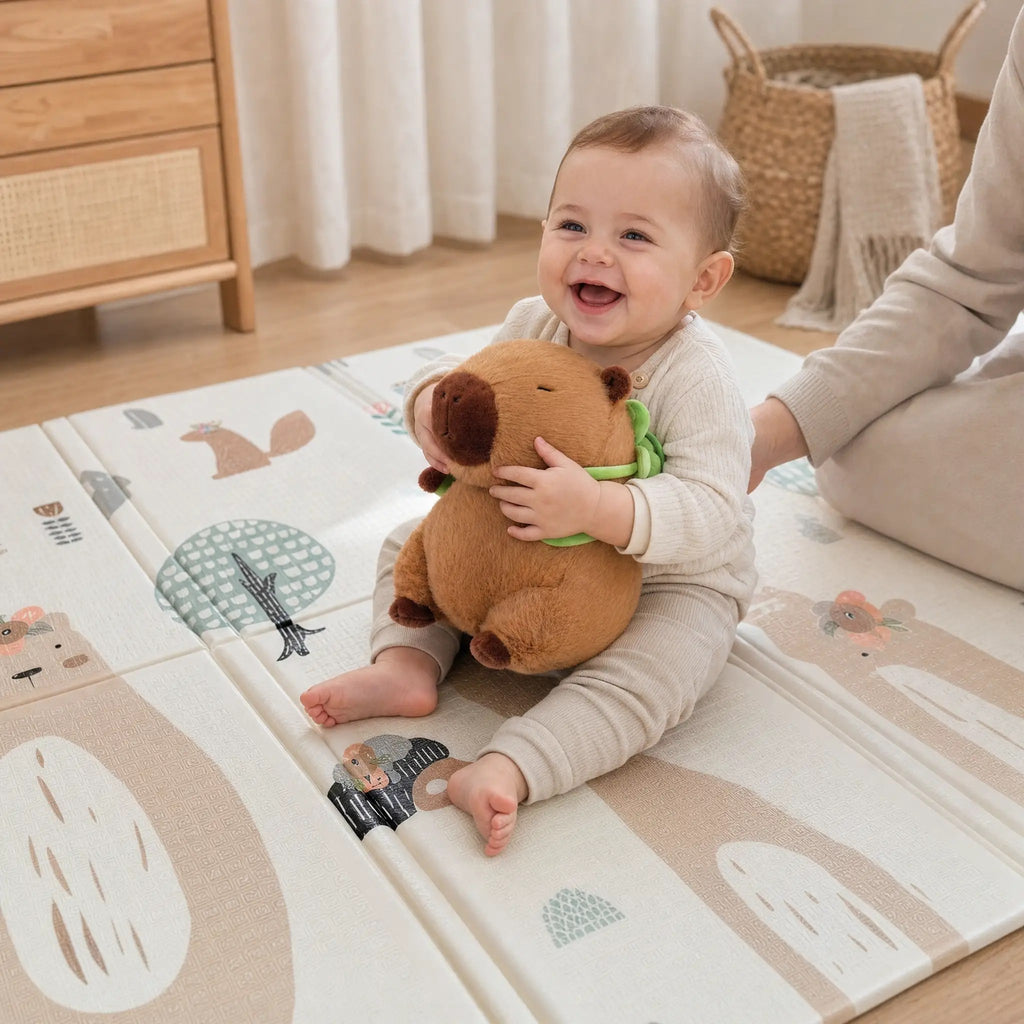 Bébé qui rit en jouant avec la peluche capybara sac à dos tortue sur le tapis de jeu ECLOA Forêt