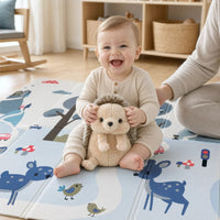 Bébé joyeux qui joue avec la peluche hérisson sur le tapis de jeu ECLOA Biche