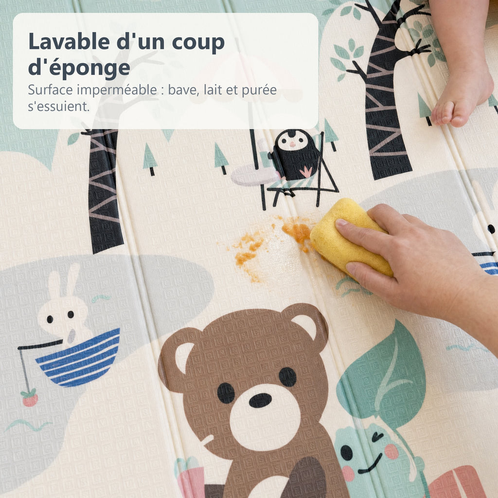 Une main essuie de la purée d'un coup d'éponge sur le tapis de jeu imperméable pique-nique et petit train