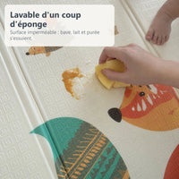 Une main essuie de la purée d'un coup d'éponge sur le tapis de jeu imperméable renard et biches
