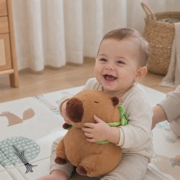 Bébé qui joue avec la peluche capybara sac à dos tortue sur un tapis de jeu ECLOA forêt